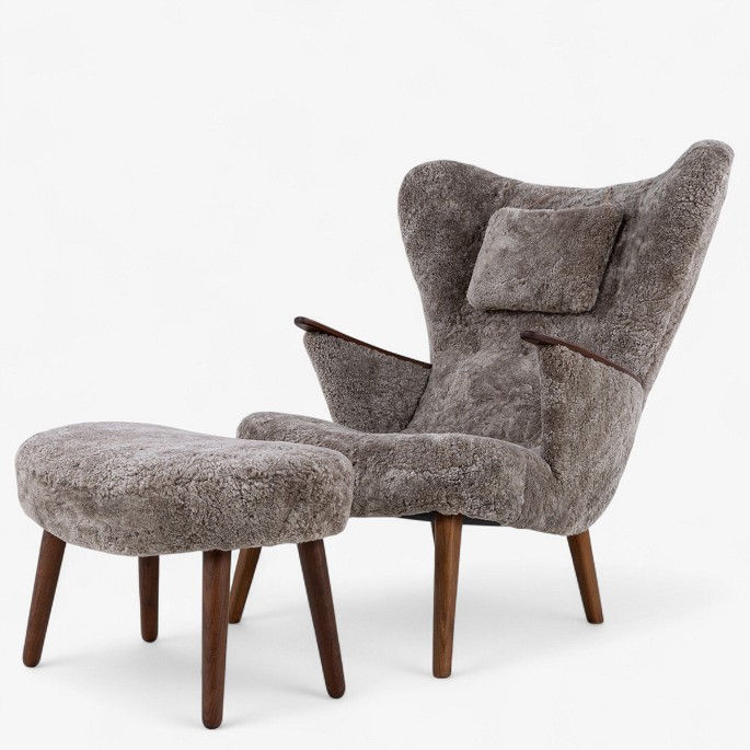 Ib Madsen & Acton Schubell.
Nybetrukket lænestol med skammel i Scandilock-lammeskind (farve: Cork 19) og 
ben i hhv. teak og elm.
1 stk. på lager

